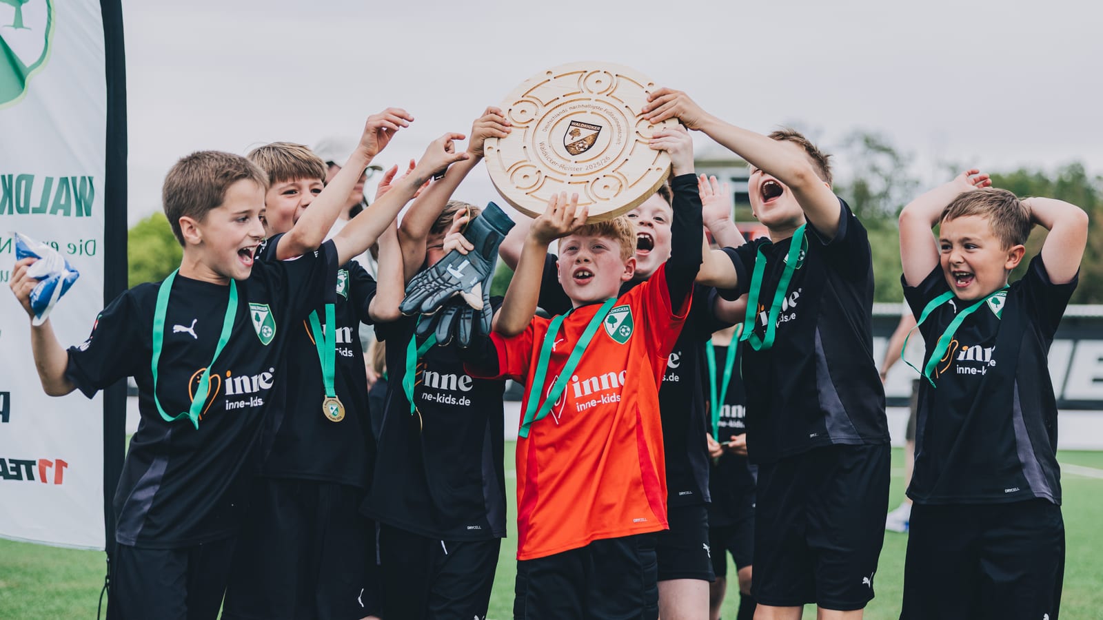 Kinder spielen Fußball auf einem Platz im Grünen